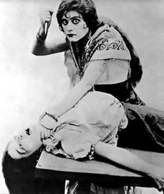 Theda Bara Makeup, Dramatic Sitting Pose, Leaning Towards Camera Pose, Growing Up Creepie Fanart, Tending To Wounds Reference, Old Person Reference, Eerie Poses, Woman Shushing, Redraw Images