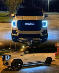 the front end of a white truck parked on top of a parking lot at night