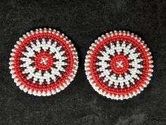 two red and white beaded circles sitting on top of a black surface