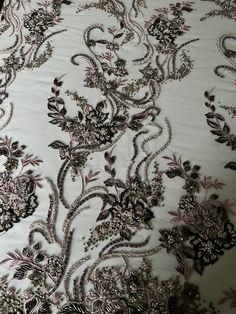 an embroidered fabric with silver and black flowers on white background, close - up view