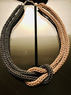 a multi - colored rope necklace hanging from a hook on a metal pole in front of a mirror