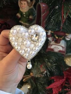 someone is holding a heart shaped ornament in front of a christmas tree with ornaments