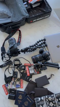 an open laptop computer sitting on top of a table next to cameras and other items