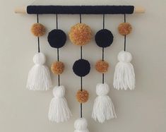 a wall hanging with tassels and pom poms in black, white and gold