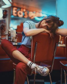 a woman sitting in a red chair with her head on her hands and legs crossed