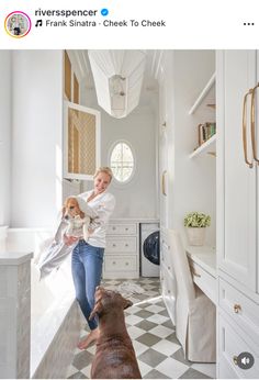 a woman holding a dog in her arms while standing next to a kitchen counter top