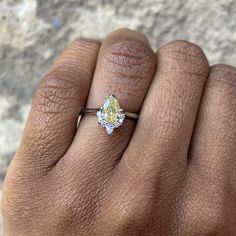 a woman's hand with a yellow diamond ring on it