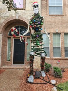 a skeleton is standing in front of a house decorated for christmas