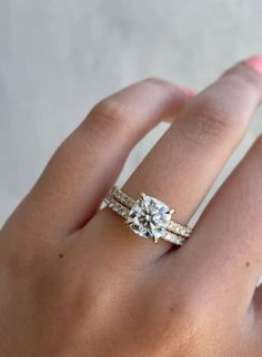 a woman's hand with a diamond ring on top of her finger and the other hand holding an engagement ring