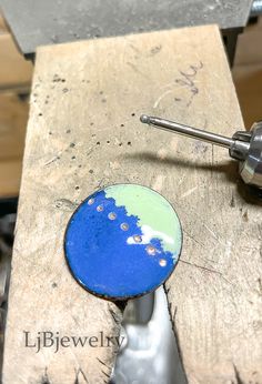 a drill is being used to make a blue and green disc with holes in it