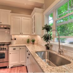 a kitchen with white cabinets and granite counter tops, stainless steel sink and dishwasher