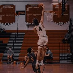 a basketball player jumping up in the air to dunk a ball while others look on