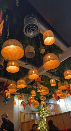 many lights hanging from the ceiling in a restaurant with people sitting at tables under them