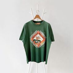 a green t - shirt hanging on a white rack