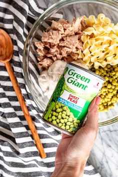 a hand holding a can of green giant pasta next to some peas and other ingredients