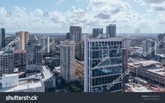 an aerial view of skyscrapers in the city with blue sky and clouds above them