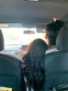 a man and woman sitting in the back seat of a car looking at each other