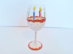 a wine glass with candles on it sitting on a white counter top next to a wall