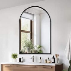 a bathroom with a large mirror above the sink and plants on the window sill