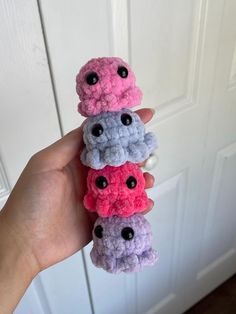 a hand holding three small crocheted items in front of a door