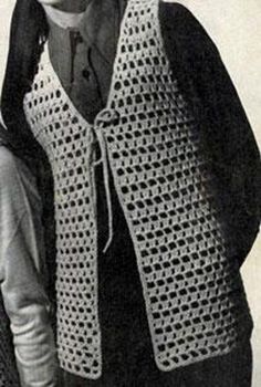 an old black and white photo of a woman wearing a crocheted sweater with hood