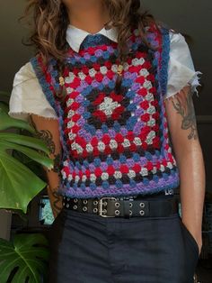 a man wearing a crocheted vest and tie with his hands in his pockets