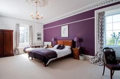 a bedroom with purple walls and white carpeted flooring is pictured in this image