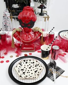 a table topped with black and white plates covered in red liquid next to a statue