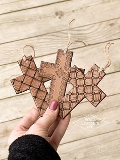 a person holding up a wooden cross ornament