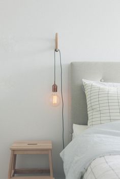 a light that is on the side of a bed next to a night stand and stool