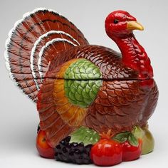 a glass turkey figurine sitting on top of grapes and fruit next to it's lid