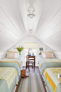 two beds in a small room with white walls and wood flooring, along with a striped rug on the floor