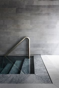 an escalator is shown in front of a gray brick wall with metal handrails