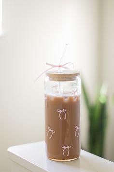 a glass jar filled with liquid sitting on top of a white table next to a potted plant