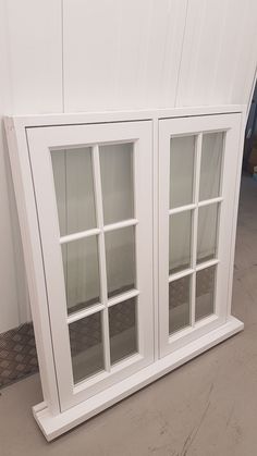 two white windows sitting next to each other on top of a cement floor in front of a wall