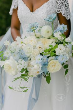 a bride holding a bouquet of white and blue flowers