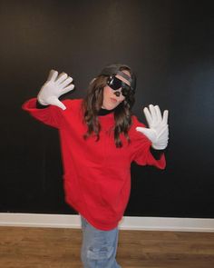 a woman in red shirt and white gloves standing on wooden floor with hands raised up