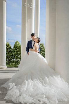 a bride and groom kissing in front of columns