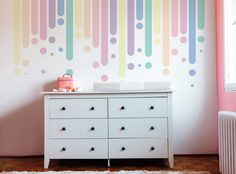 a baby's room with a dresser and wall mural