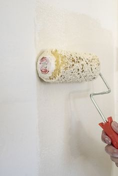 a person using a paint roller to paint a wall