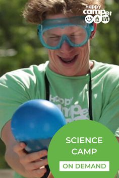 a man holding a blue ball and wearing goggles with the words science camp on it