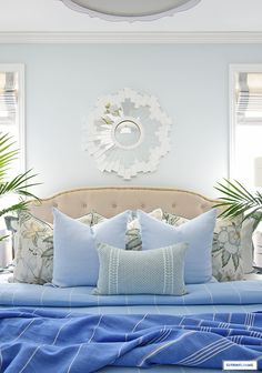 a bed with blue sheets and pillows on top of it next to two planters