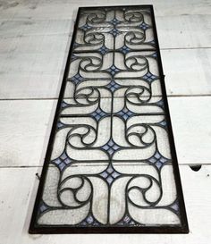 an old stained glass window with decorative designs on the bottom and sides, sitting on a white wooden floor