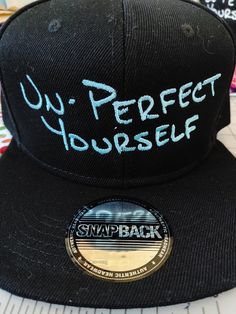 All black 100% polyester snapback hat with the words "UN-PERFECT YOURSELF" stitched across the front in customer choice of color. Please see second picture of listing to choose your color, type the code or color name in the personalization box. Having been a perfectionist most of my life, I needed a reminder that it is not the right path to take. Even if I falter, I can remember to just keep un-perfecting myself. It's okay to make mistakes - be kind to yourself. Make Mistakes, It's Okay, Making Mistakes, Be Kind To Yourself, Custom Hats, Snapback Hat, Color Names, Be Kind, Snapback Hats