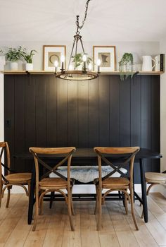 a dining room table with two chairs and some plants on the top shelf above it