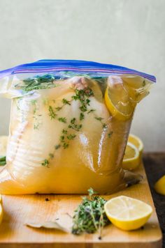 a bag filled with lemons and herbs on top of a cutting board