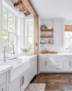 a white kitchen with wood floors and open shelving on the wall above the sink