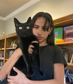 a woman holding a black cat in her arms and looking at the camera with an intense look on her face