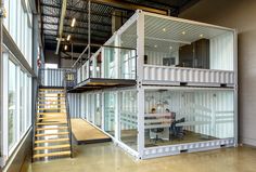 the inside of a shipping container with stairs leading up to it and a person sitting at a desk in front of them