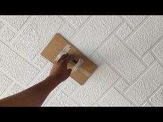 a person is painting a wall with white paint on it and cardboard box in the foreground